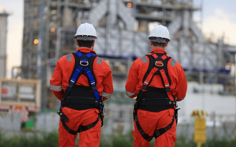 Industrial workers in orange uniforms and helmets